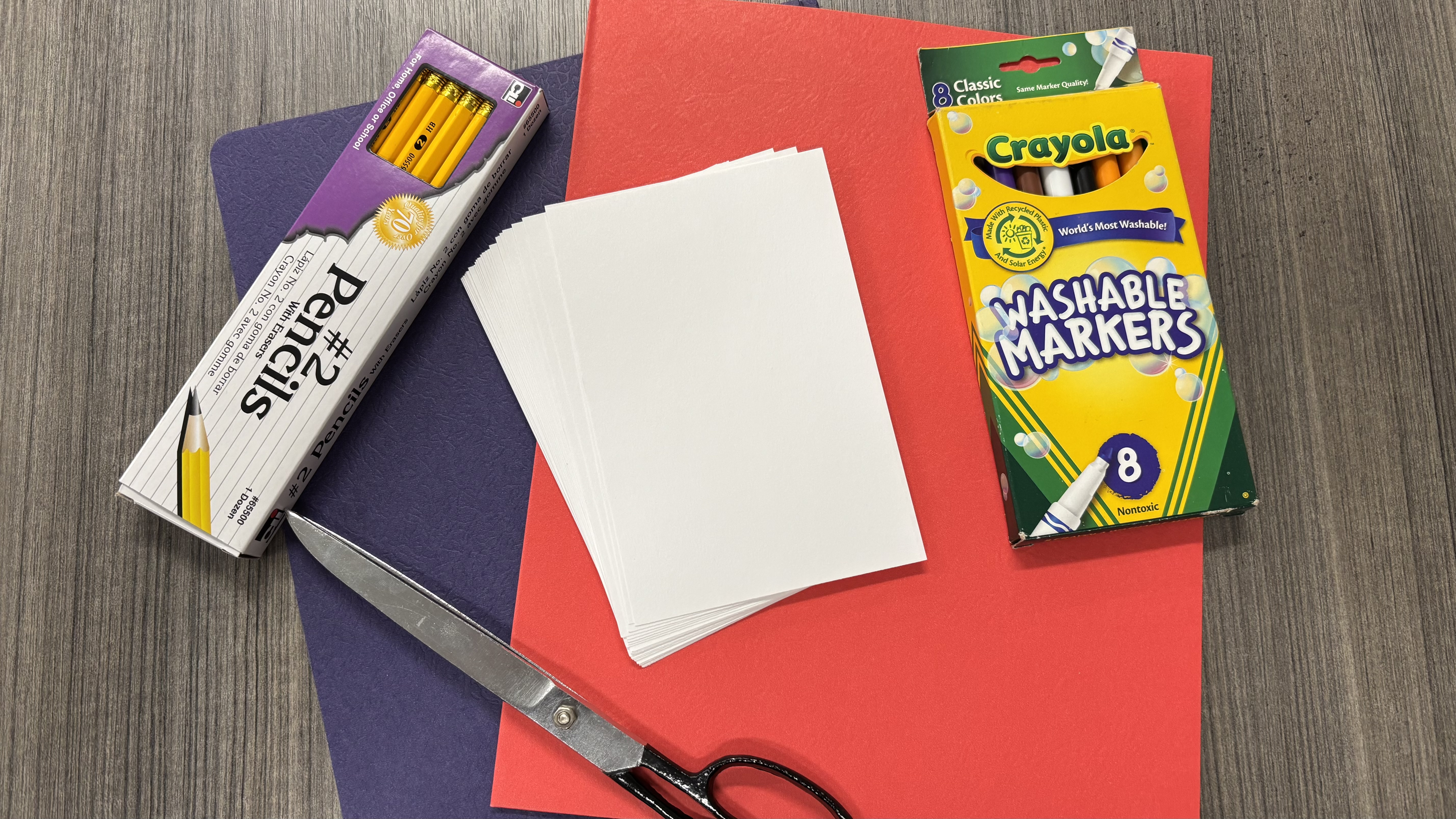 Paper, pencils, scissors, and other school supplies set for a picture
